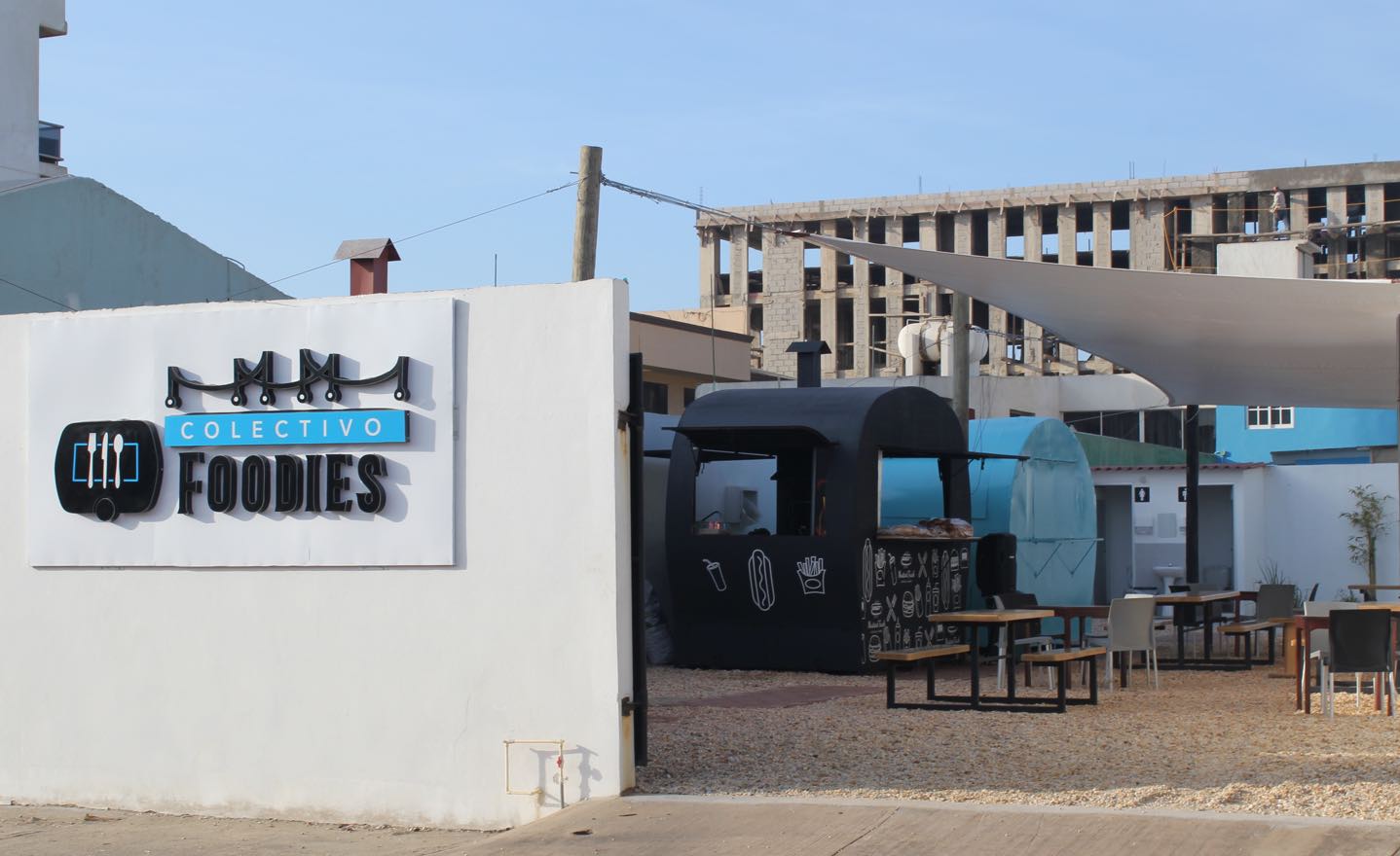 espacio de Colectivo Foodies con carritos de comida street food y mesas picnic on una pared en la entrada y el logo visible